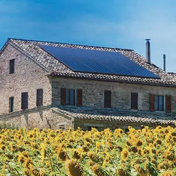 European house with solar panels surrounded by sunflowers European house with solar panels surrounded by sunflowers